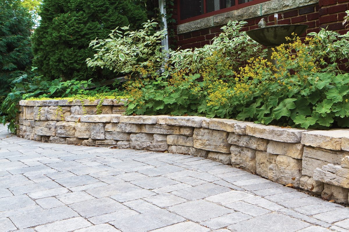 rock wall garden with paver patio area by Sutherland Landscape